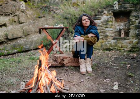 Jeune femme assise près d'un feu pendant un pique-nique en hiver. Banque D'Images