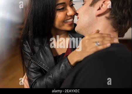 Un jeune couple multiethnique embrasse chez lui. Elle est noire indienne et il est caucasien. Banque D'Images