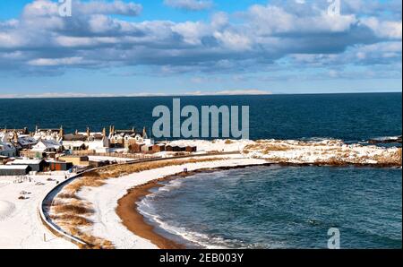 FINDOCHTY MORAY FIRTH SCOTLAND CIEL BLEU ET VUE D'HIVER SUR LA PLAGE ENNEIGÉE ET LES MAISONS DE VILLAGE Banque D'Images