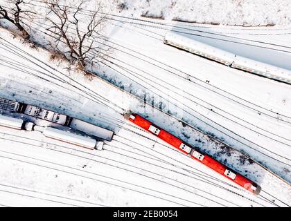 Vue de dessus des trains de chargement et de la passerelle diesel - DMU. Vue aérienne de dessus de drone volant de trains de marchandises couverts de neige sur le tra de chemin de fer Banque D'Images