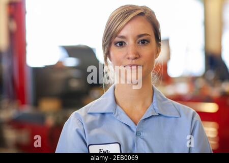 Portrait d'une jeune femme mécanicien de race blanche dans un atelier de réparation automobile Banque D'Images