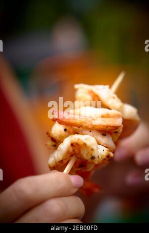 Cuisine de rue asiatique, crevettes sur une brochette étant tenue par une femme Banque D'Images