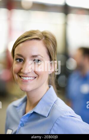 Portrait d'une jeune femme mécanicien de race blanche dans un atelier de réparation automobile Banque D'Images