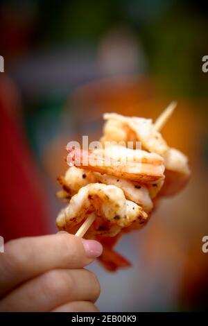 Cuisine de rue asiatique, crevettes sur une brochette étant tenue par une femme Banque D'Images