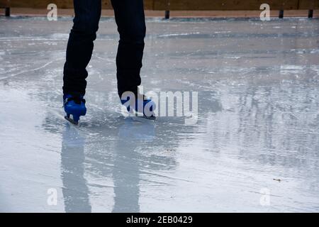 Garçon portant des patins apprenant à skate sur la patinoire humide.Patineuse débutant.Réflexion.Résumé vacances d'hiver arrière-plan.Réalisation des objectifs. Banque D'Images