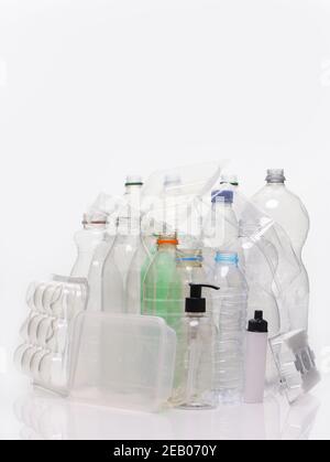 Collection de matériaux à base de plastique domestique, filés sur un fond blanc avec réflexion. Flacons, plateaux alimentaires, conteneur à pompe prêt pour le recyclage. Banque D'Images