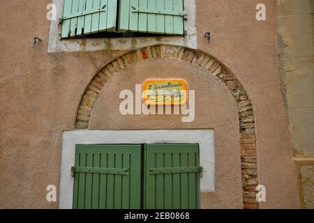 Volets de fenêtre en bois vert typique sur un mur en stuc ocre avec un panneau de rue vitré peint à la main à Aubagne, Bouches-du-Rhône, Provence France. Banque D'Images