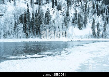 Rive glacée du lac avec forêt enneigée. Par temps froid, lit de rivière gelé en raison de la forte pression froide Banque D'Images