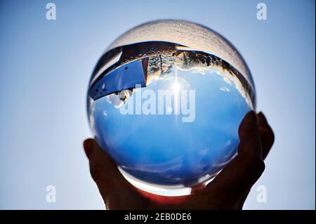 Regardez à travers une boule de cristal sur un paysage d'hiver, qui peut être vu à l'envers à travers le reflet. Banque D'Images