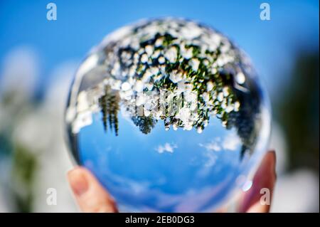 Regardez à travers une boule de cristal sur un paysage d'hiver, qui peut être vu à l'envers à travers le reflet. Banque D'Images