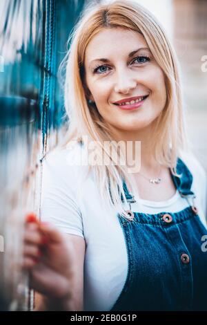 Portrait d'une femme blonde aux yeux bleus avec un Jean et des bretelles Banque D'Images