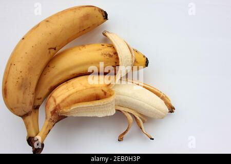 Bananes trop mûres sur fond blanc.Gros plan d'une banane à moitié pelée.Vue de dessus Banque D'Images