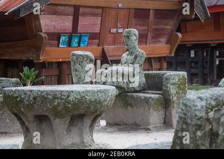 L'Indonésie, Sumatra, l'île de Samosir, Lac Toba, Ambarita, Siallagan village, ancienne en pierre de Batak des chaises et une table en pierre, qui constituent un ancien co Banque D'Images