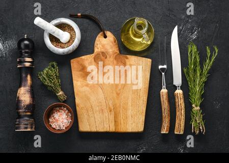 Vue en hauteur de la planche à découper en bois vide avec épice pour steak, couteau et fourchette avec poignée en corne Banque D'Images