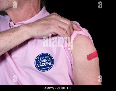 Homme adulte senior montrant son plâtre adhésif sur son Covid-19 vaccination avec un autocollant indiquant qu'il a reçu son vaccin Banque D'Images