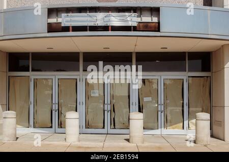 Magasin abandonné au centre commercial avec du papier déchiré sur les portes et panneau au néon déchiré Banque D'Images