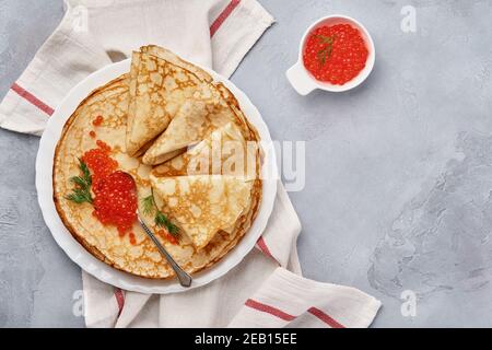 Crêpes, crêpes fines, crêpes russes avec caviar rouge sur une assiette grise. Arrière-plan en marbre. Copier l'espace. Vue de dessus. Banque D'Images