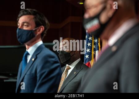 Washington, États-Unis. 11 février 2021. Le sénateur Raphael Warnock (D-GA), au centre, et le chef de la majorité au Sénat Charles Schumer, D-NY, écoutent à droite comme le sénateur Jon Ossoff (D-GA), parle au Capitole des États-Unis le 11 février 2021 à Washington, DC. Schumer a parlé de la nécessité d'adopter le plan de secours de la COVID-19 dans le cadre de la résolution budgétaire. Photo de Ken Cedeno/Sipa U. sa crédit: SIPA USA/Alay Live News Banque D'Images