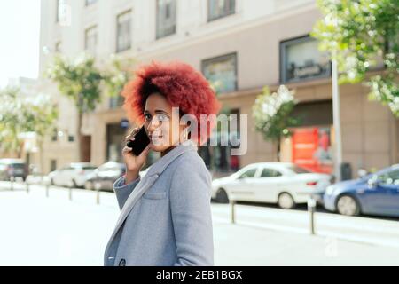 belle femme aux cheveux afro parlant depuis son smartphone Banque D'Images