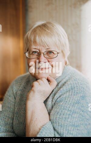 Gros plan portrait authentique et franc de femme blonde senior de grande taille à la maison. Portrait d'une femme mûre à lunettes Banque D'Images