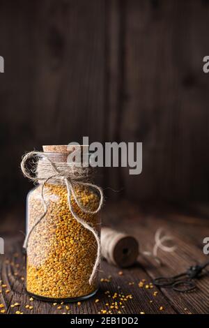 Complément alimentaire sain, pollen d'abeille super-alimentaire dans une bouteille en verre avec copie sur fond rustique en bois Banque D'Images