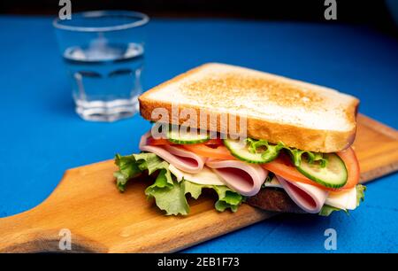 Sandwich avec du bacon et des légumes sur fond sombre. Macro Banque D'Images