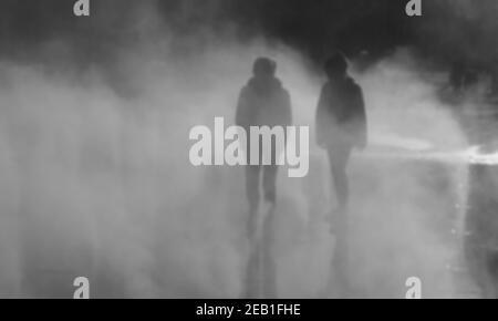 Photo floue d'un garçon et d'une fille jouant dans la brume d'eau de fontaine le jour de l'automne. Paris, France. Photo en noir et blanc. Banque D'Images