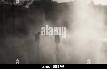 Photo floue de deux enfants jouant à la marche dans la brume d'eau de fontaine le jour d'automne. Paris, France. Photo sépia. Banque D'Images