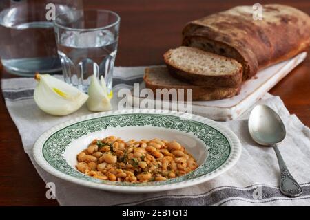 Ragoût de haricots, ciabatta et oignons sur une table en bois. Banque D'Images