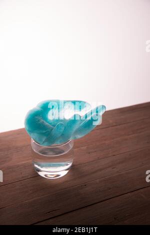 Eau gelée avec un colorant bleu en forme de main humaine sur un verre d'eau. Le concept. Banque D'Images