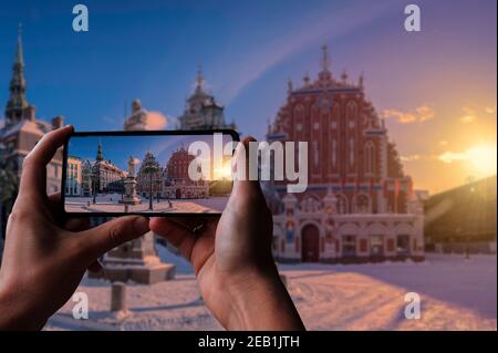 Touriste prenant une photo de la place de l'Hôtel de ville pendant le coucher du soleil en hiver à Riga, Lettonie Banque D'Images