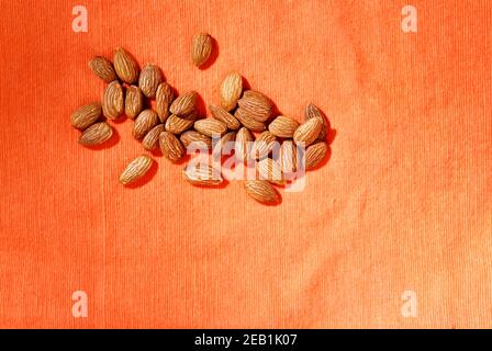 Tas d'amandes décortiquées marron sur fond orange Banque D'Images