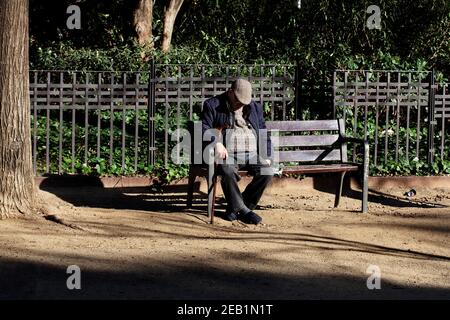 Le vieil homme s'est assis sur le banc du parc, Barcelone, Espagne. Banque D'Images