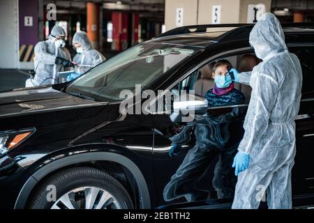 Travailleur médical mesurant la température de la femme par la fenêtre de la voiture avant de quitter la zone de quarantaine. Restez à la maison Banque D'Images