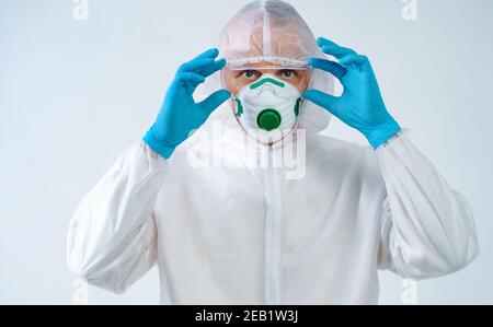 Le professionnel de la santé en costume de protection et masque médical met des lunettes. Concept de soins de santé. Banque D'Images