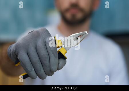 Outil à main nécessaire. Gros plan de la main de la pince de maintien du jeune réparateur Banque D'Images