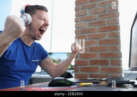 Le joueur masculin dans le casque réagit émotionnellement au jeu gagnant Banque D'Images