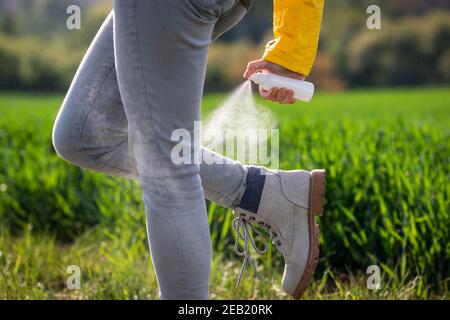 Insectifuge contre la tique. Femme randonneur appliquant un produit anti-moustiques sur les jambes et la chaussure à l'extérieur Banque D'Images