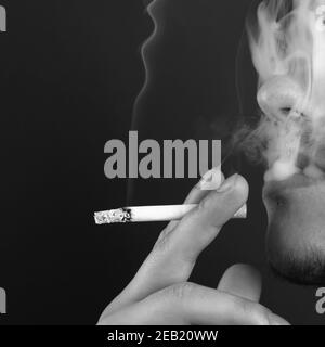 l'homme fume une cigarette dans la fumée blanche à l'obscurité arrière-plan Banque D'Images