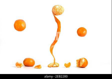 Peeling Tangerines ou Clementines avec un peu de vol stationnaire dans l'air, isolé sur fond blanc Banque D'Images