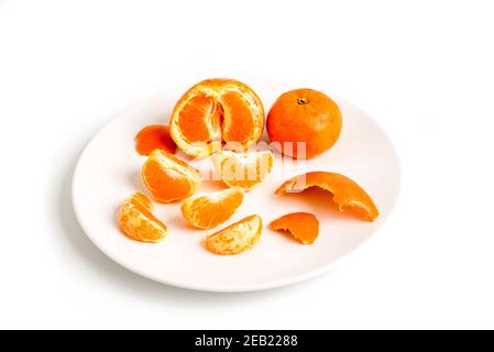 Epaillement de tangerines ou de clémentines dans une plaque blanche, isolée sur fond blanc Banque D'Images