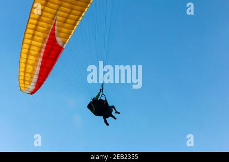 Deux personnes parapente haut dans le ciel, tissu coloré éclairé, fond d'avion Banque D'Images