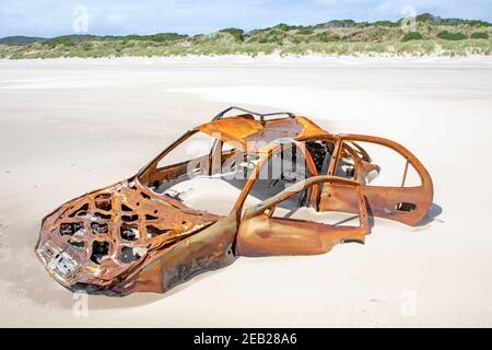 Voiture rouillée coincée dans le sable sur Ocean Beach Strahan Banque D'Images