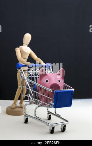 Un mannequin porte un chariot dans lequel il porte une banque de porc rose pour faire du shopping Banque D'Images