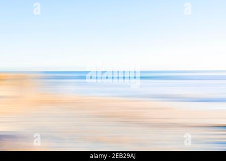 La plage côtière est floue dans des tons doux de bleu et de marron. Banque D'Images