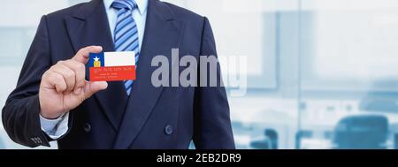 Image rognée d'un homme d'affaires tenant une carte de crédit en plastique avec drapeau imprimé du Chili. Arrière-plan flou. Banque D'Images