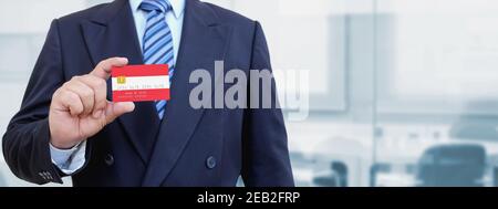 Image rognée d'un homme d'affaires tenant une carte de crédit en plastique avec drapeau imprimé de l'Autriche. Arrière-plan flou. Banque D'Images