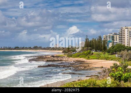 Vue sur la plage de Mooloolaba, Queensland, Australie, montrant les appartements entourés de verdure, sous un ciel nuageux. Banque D'Images