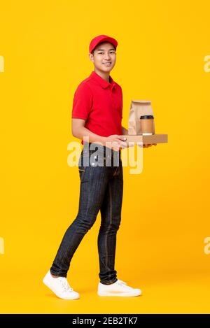 Jeune asiatique homme fast food équipe en uniforme rouge livrant repas à emporter sur fond de studio isolé jaune Banque D'Images