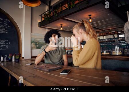 Beau jeune homme parlant à une femme qui boit du café dans un cadre moderne café Banque D'Images